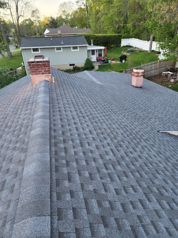 A finished grey shingle roof with a brick chimney