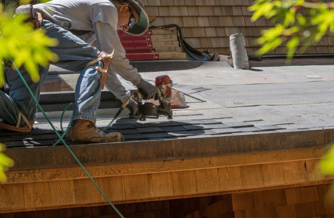 A roofer cutting material during a roof repair