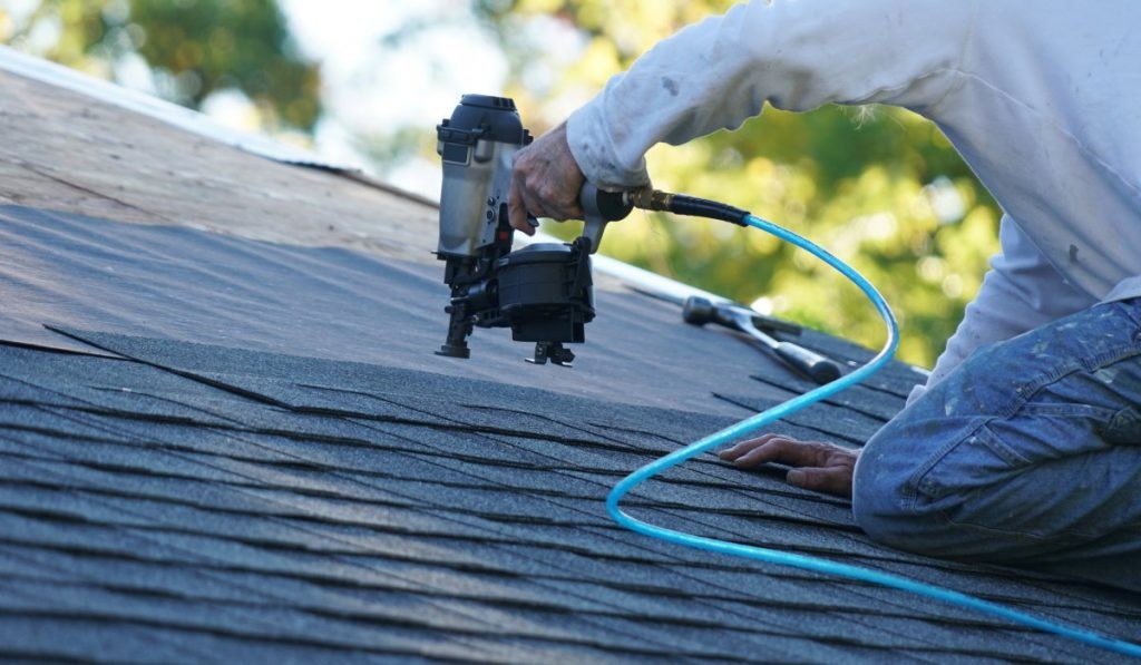 A roofer nailing shingles during a roof repair